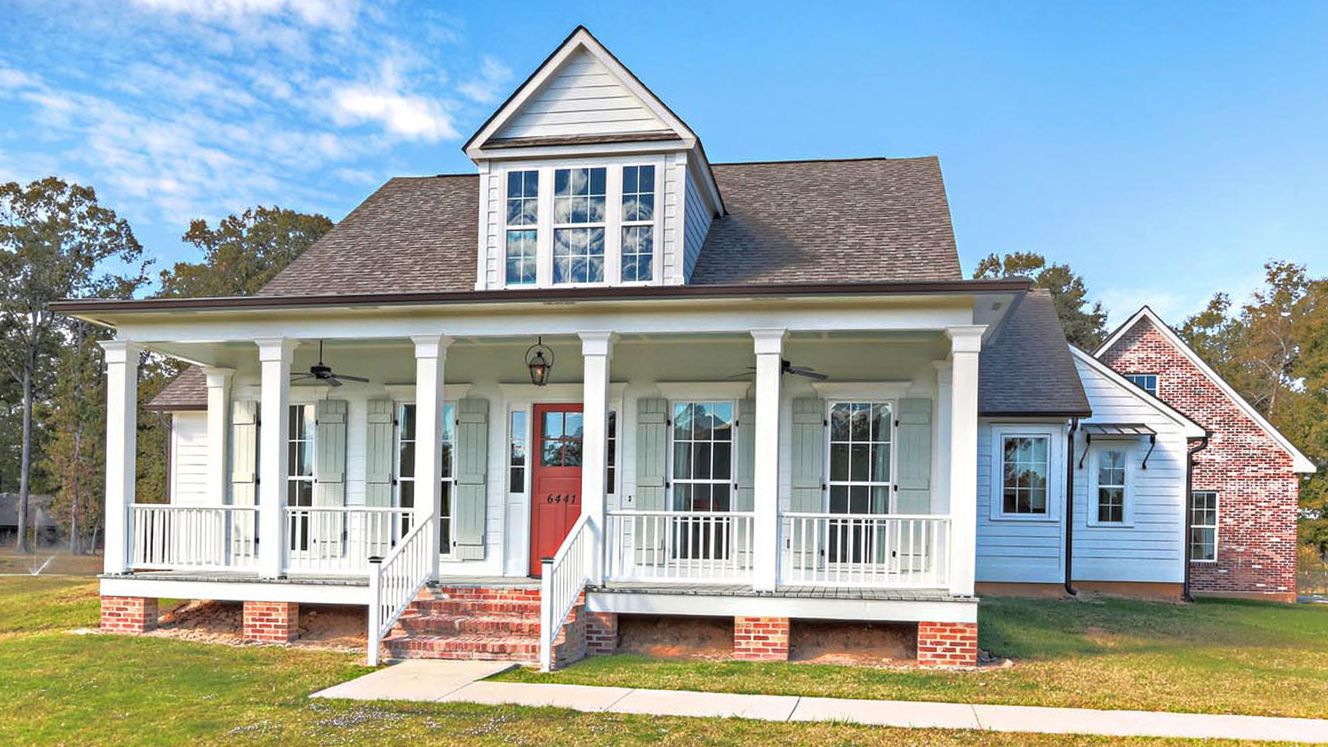 Raised Acadian farmhouse built by Carroll Construction in a designated flood zone Acadian-style raised home built in a flood zone with elevated slab foundation and front porch