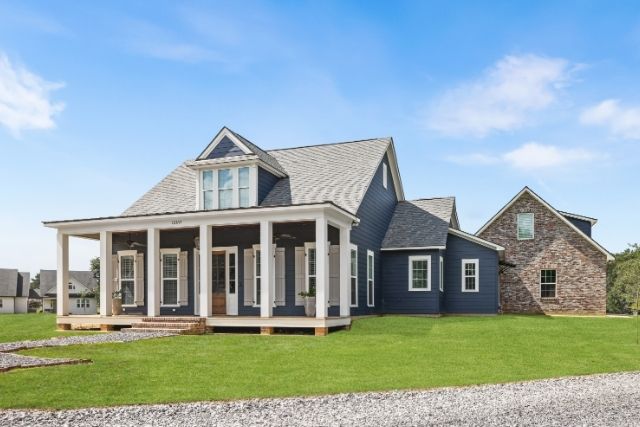 Acadian Farmhouse with gabled roof, deep front porch, and mixed brick and board-and-batten siding