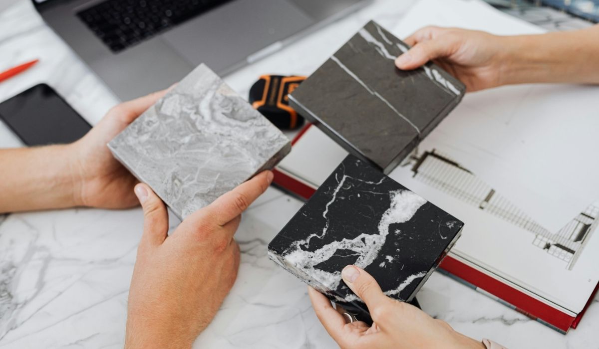 Quartz countertop samples being reviewed in a design meeting Hands holding quartz countertop samples during a custom home design meeting