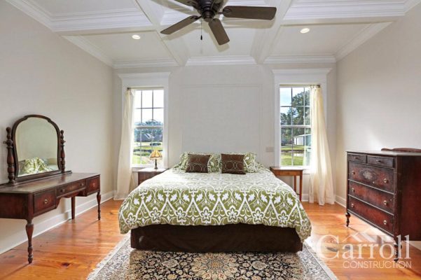 Master bedroom with heart pine floors, coffered ceiling, and windows with custom pediments flanking the bed