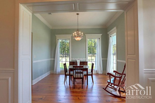 Paneled cased opening leading to dining room with chandelier