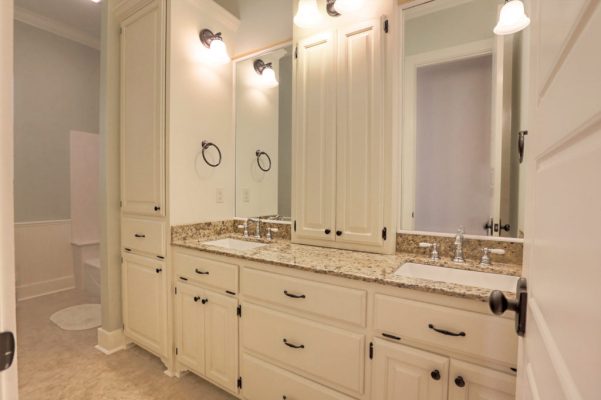 Kids bathroom vanity with central linen tower, sconce lighting, and granite countertops
