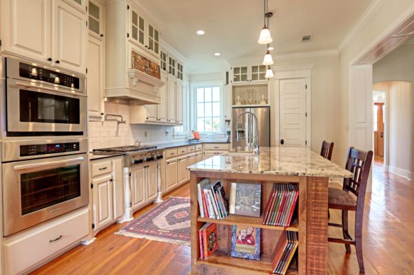 Kitchen view toward refrigerator with reclaimed wood island and built-in bookcase