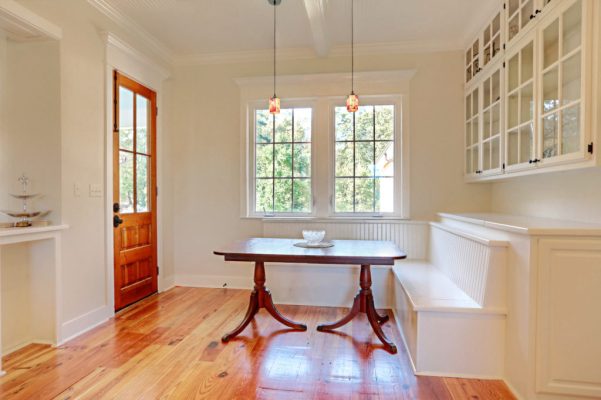 Breakfast area with built-in bench seating, glass front display cabinets, and stained rear entry door