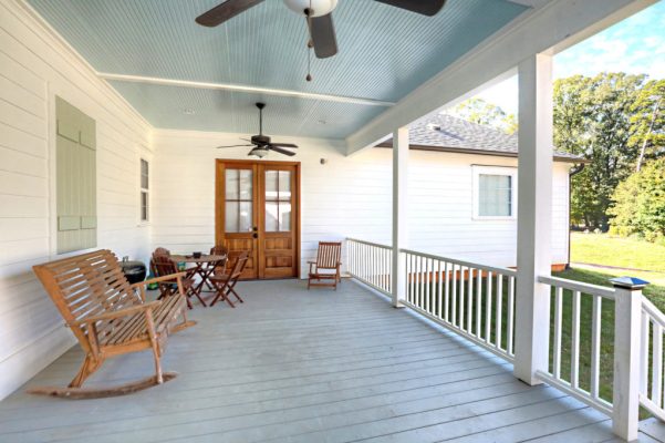 Back porch with handrails, sky blue ceiling, rocking chair, and double doors to master bedroom