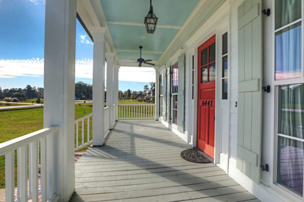 Side view of front porch with sky blue ceiling, red front door, and handrails
