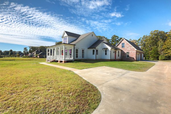 Dramatic angled view of Acadian farmhouse front elevation with red door and dormer
