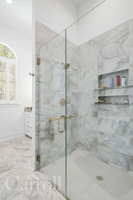 Zero-entry master shower with horizontal porcelain tile and brass hardware, designed for aging in place