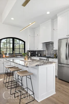 Vertical view of kitchen with granite island, Thor range, and counter-height stools