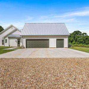 Exterior view of the Dittmar Liberty home highlighting painted garage doors, Generac backup generators, a gravel approach, and the charm of rural living. Dittmar Home – Liberty plan, 2,574 SF – exterior view facing garage with painted doors, Generac generators, and gravel approach.